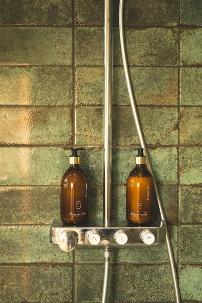 Douche à l’italienne aux carreaux verts et produits de bain