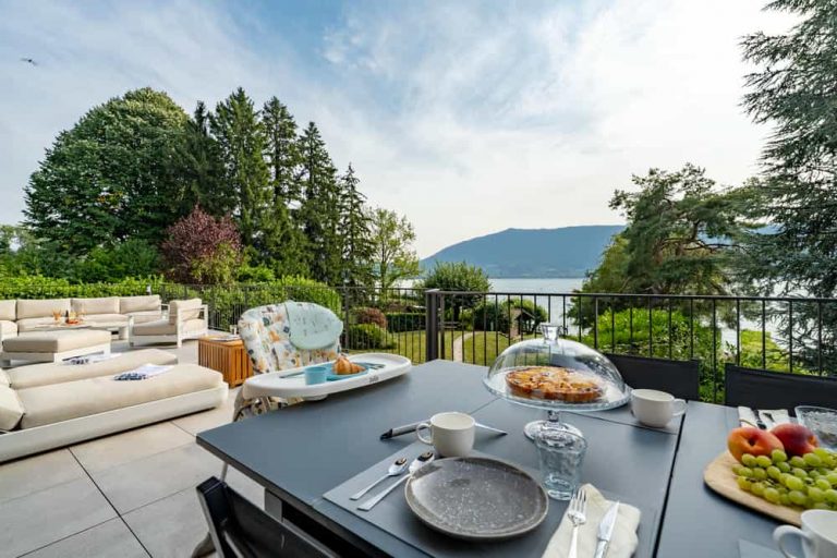 Terrasse avec canapés et table dressée face au lac